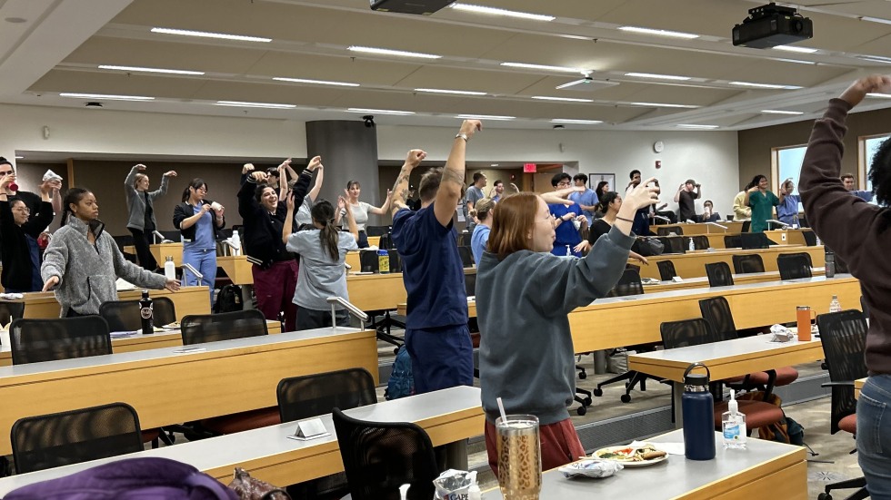 students across the whole lecture hall with arms up dancing