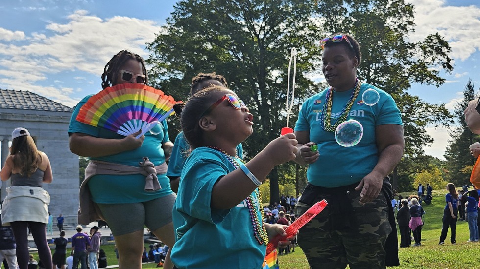 child blowing bubbles in a crowd of folks at the walk