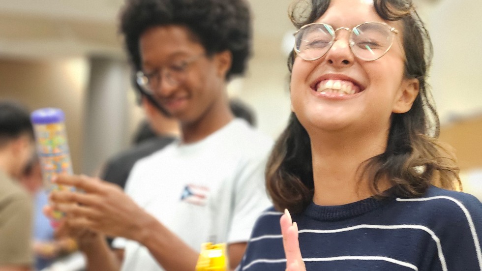 student laughing while tapping a tambourine